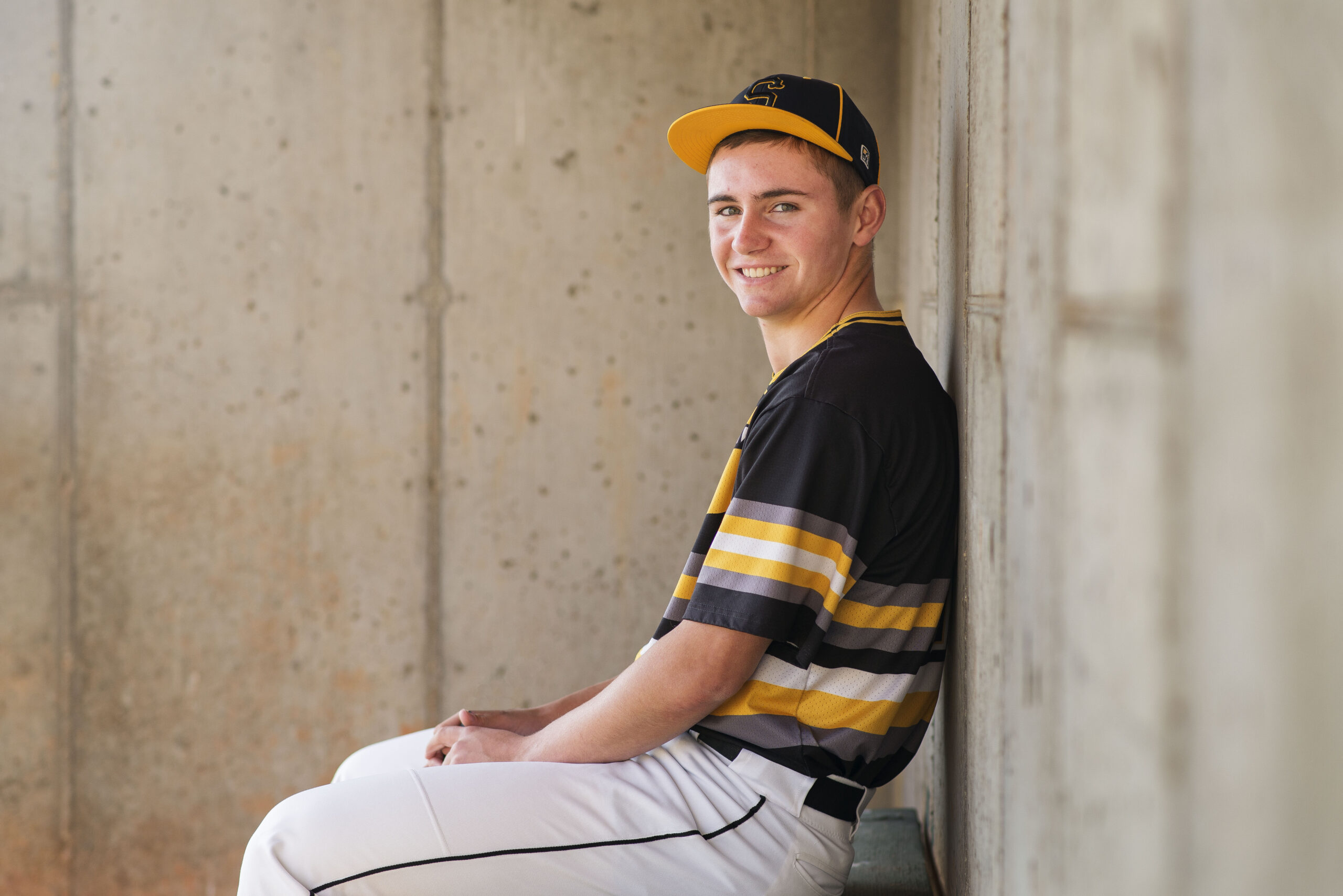 senior boy smiles in baseball uniform for senior photos